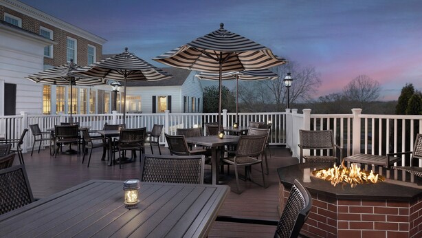 A deck with outdoor seating, a fire pit, and umbrellas. - Virginia Crossings Hotel (Glen Allen)