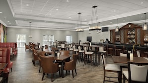 A spacious hotel lobby with multiple seating areas, a bar, and a television mounted on the wall. - Virginia Crossings Hotel (Glen Allen)