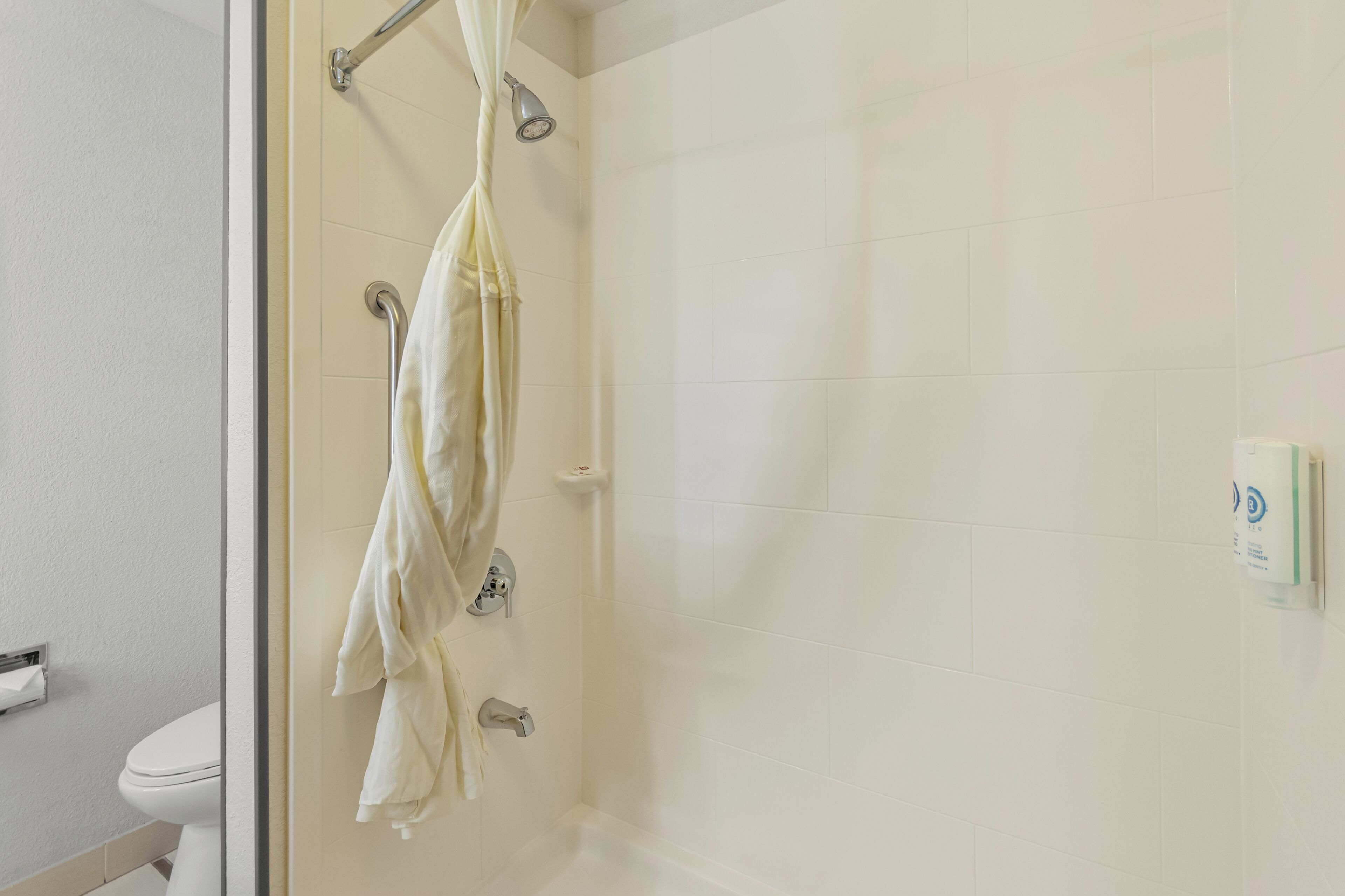 A bathroom with a shower, toilet, and towel rack.