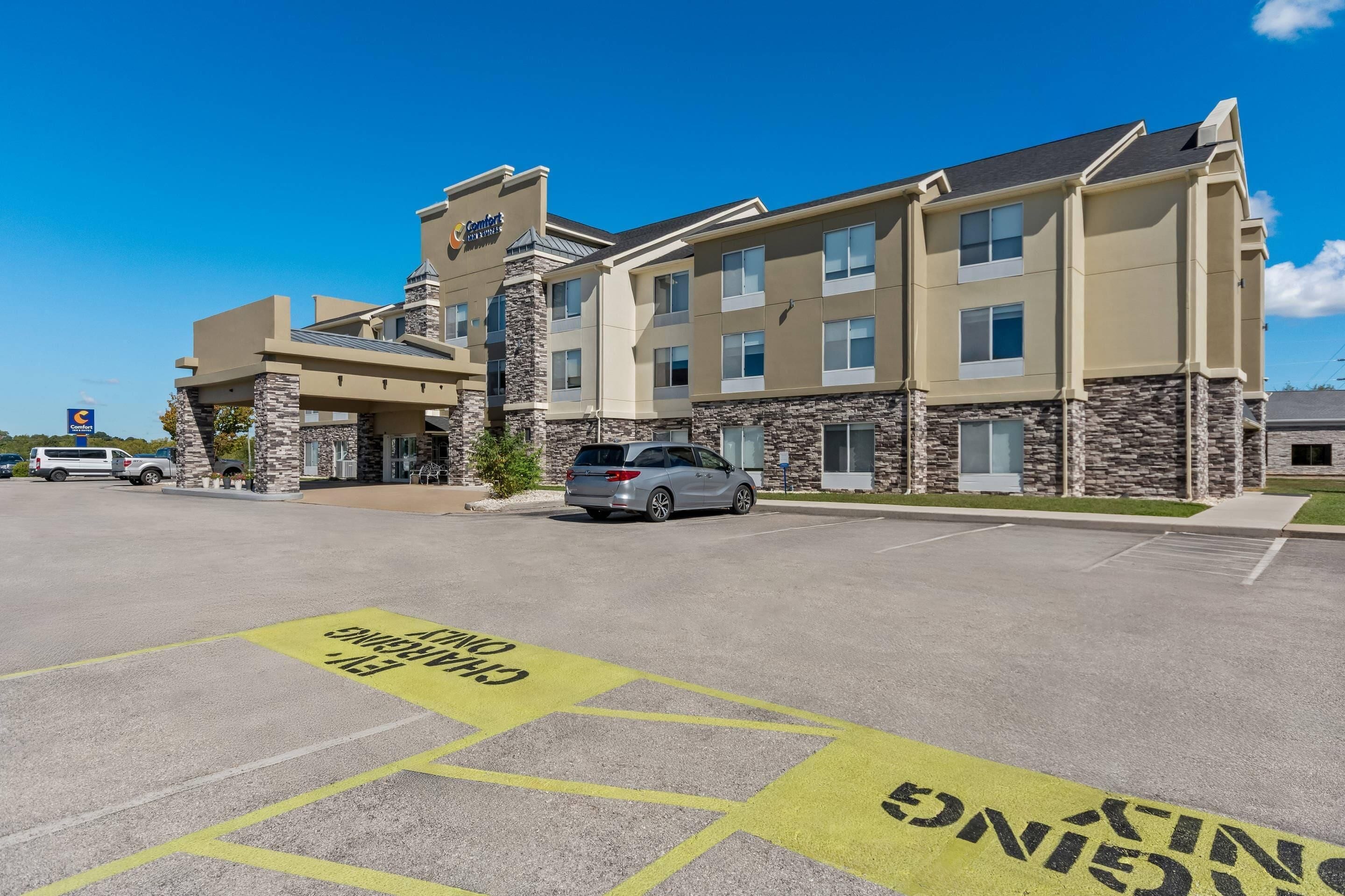 Um hotel Comfort Inn com estacionamento e um edifício com detalhes em pedra e várias janelas.