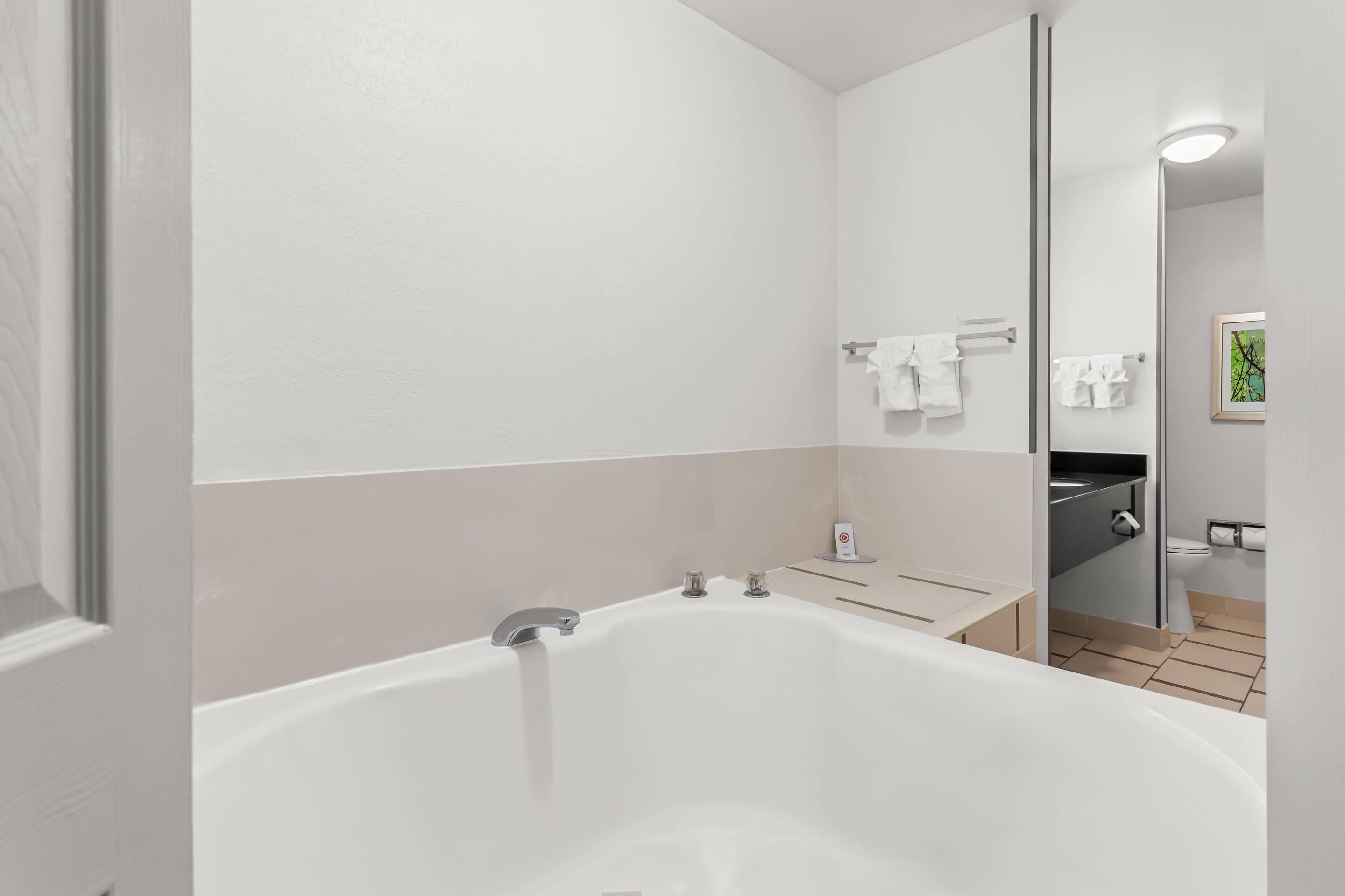A modern bathroom with a large bathtub, a toilet, and a sink.
