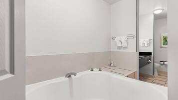 A modern bathroom with a large bathtub, a toilet, and a sink.