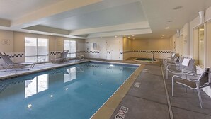 A swimming pool with lounge chairs and a tiled wall. - Spark by Hilton Central Point Medford (Central Point)