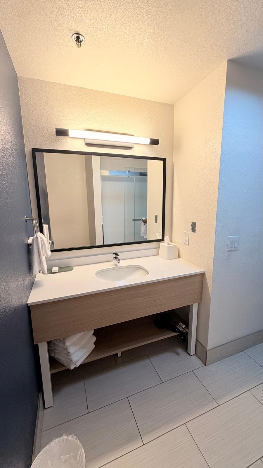 Een moderne badkamer met een grote spiegel, een wastafel en een handdoekhouder.