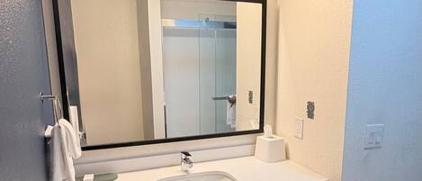 Een moderne badkamer met een grote spiegel, een wastafel en een handdoekhouder.