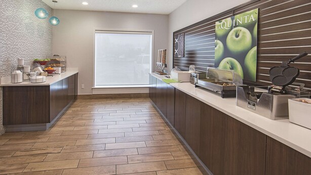 A modern kitchen with a breakfast bar, a large window, and a poster advertising La Quinta. - Spark by Hilton Central Point Medford (Central Point)