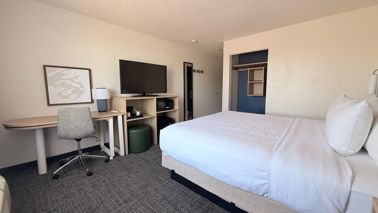 Une chambre d’hôtel comprenant un lit, un bureau, une chaise, une télévision et une armoire.