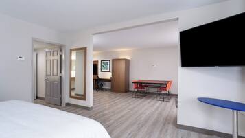 Una habitación de hotel con cama, escritorio, silla, televisor y una mesita.