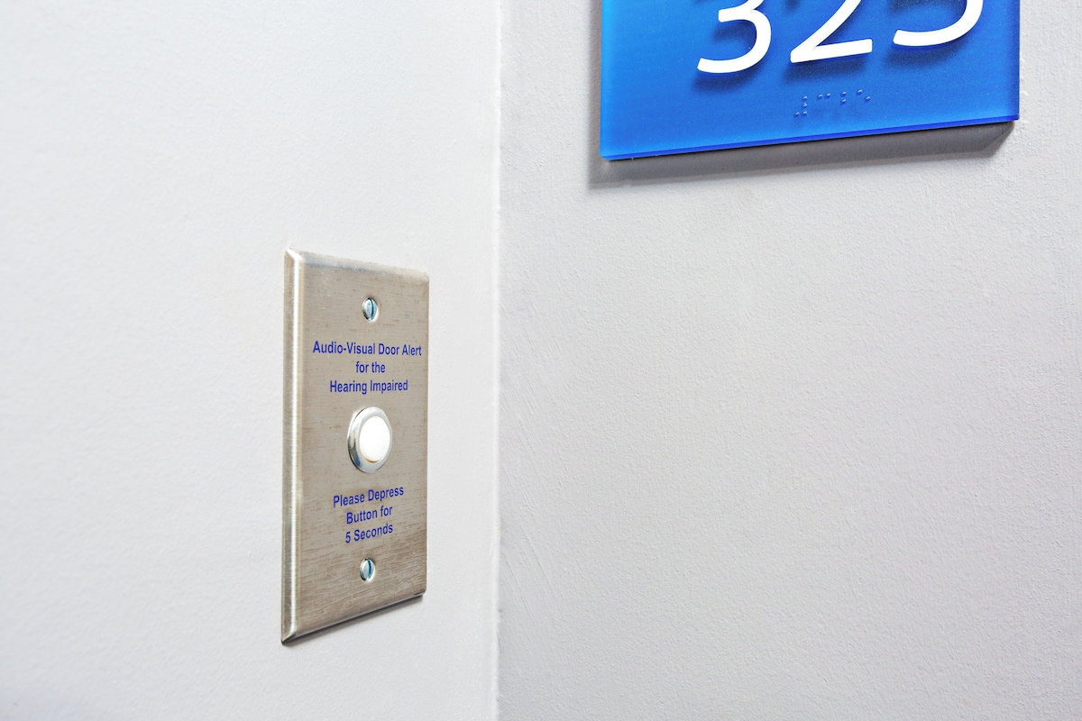 A doorbell with an audio-visual alert for the hearing impaired and a blue sign with the number 325.