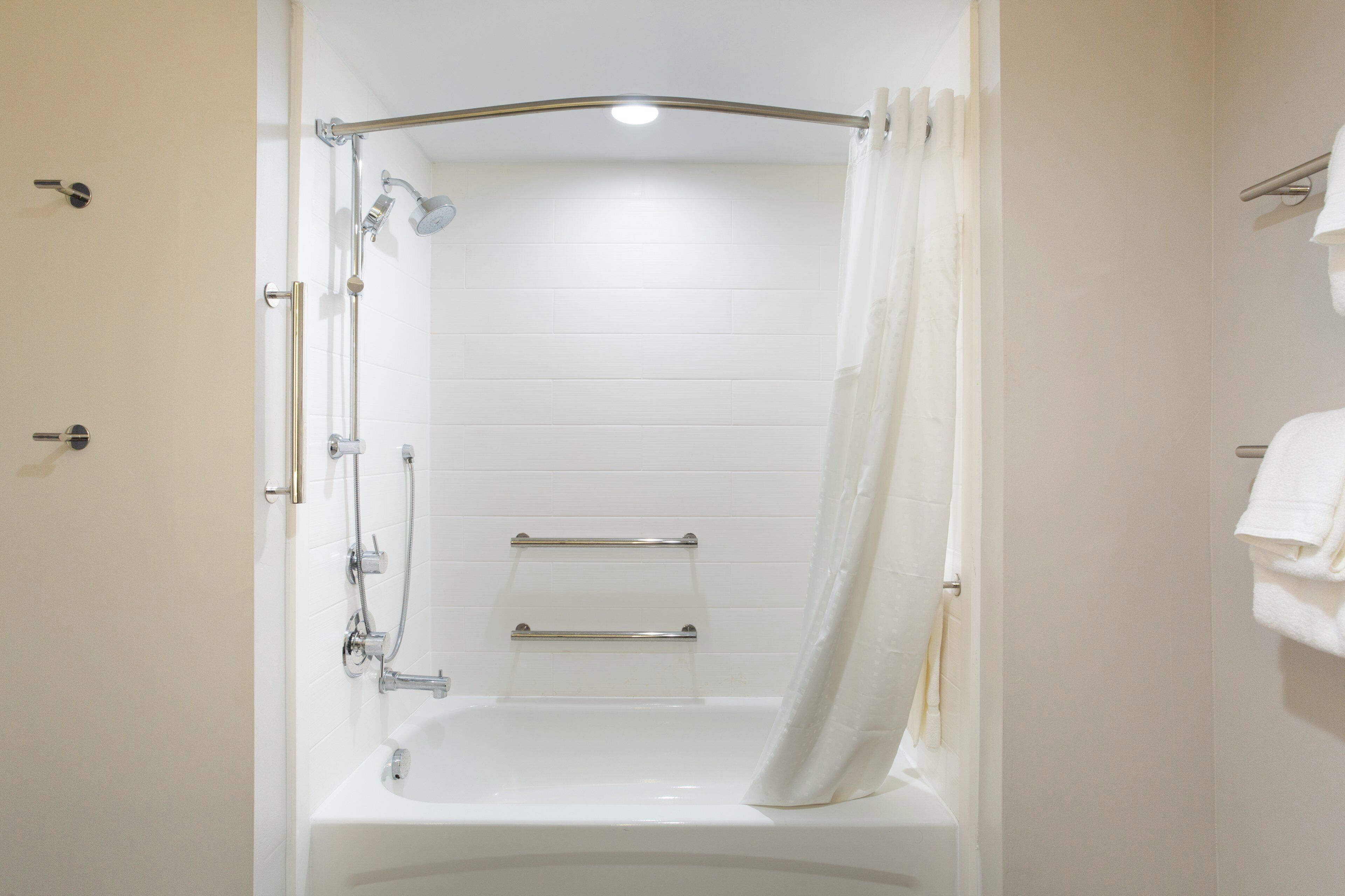 Un baño con bañera, ducha y barra para toallas.