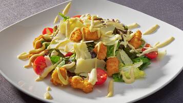 Une assiette blanche contenant une salade composée de laitue, de tomates, de croûtons et d’une sauce crémeuse.