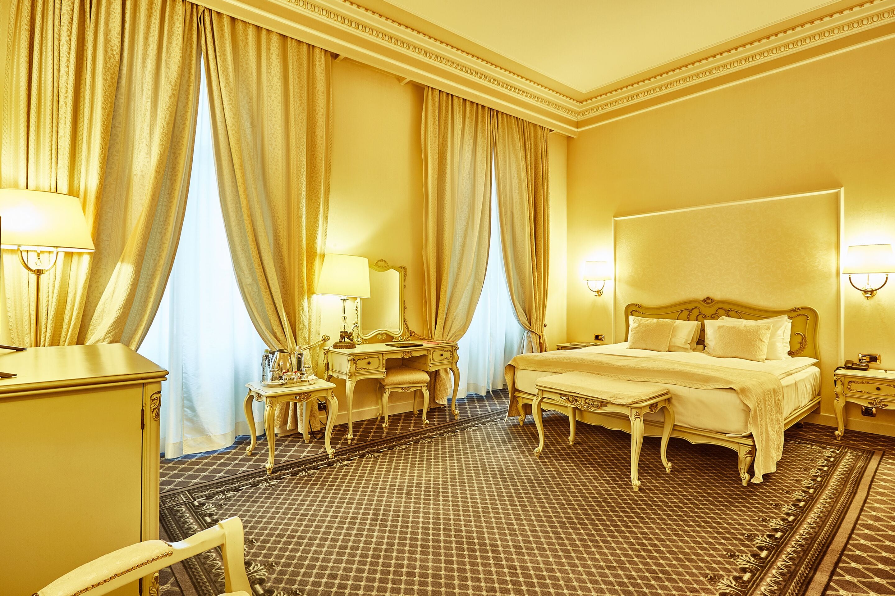 Una habitació d'hotel amb un llit gran, un escriptori amb una làmpada, una cadira i un armari.