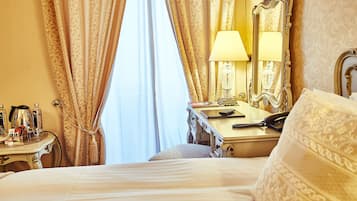 A hotel room with a bed, a bedside table with a lamp, a mirror, and a dresser.