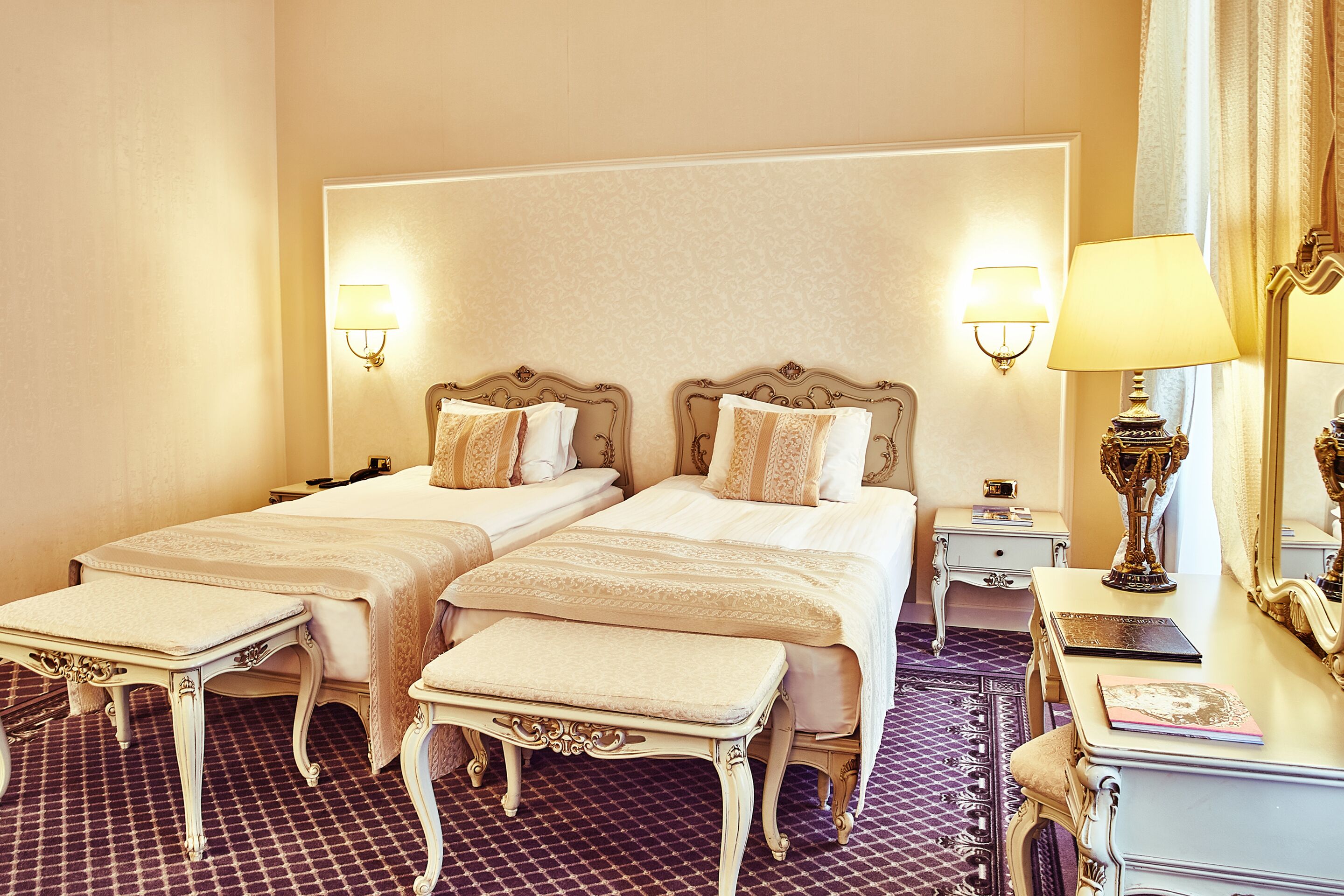 Une chambre d’hôtel avec deux lits, une table de chevet, une commode et un miroir.