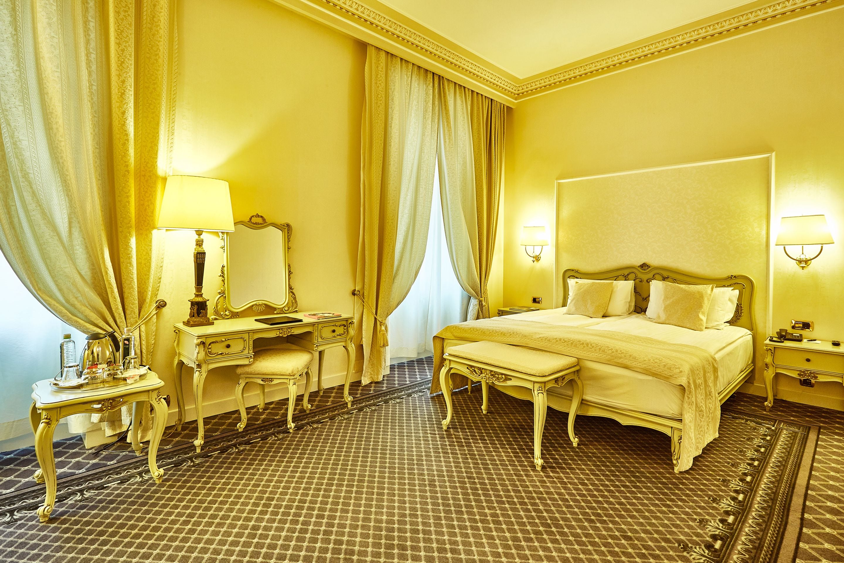 A hotel room with a large bed, a bedside table, a mirror, a desk, and a chair.