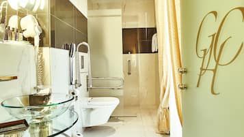 Un baño moderno con lavamanos de vidrio, inodoro blanco y zona de ducha.