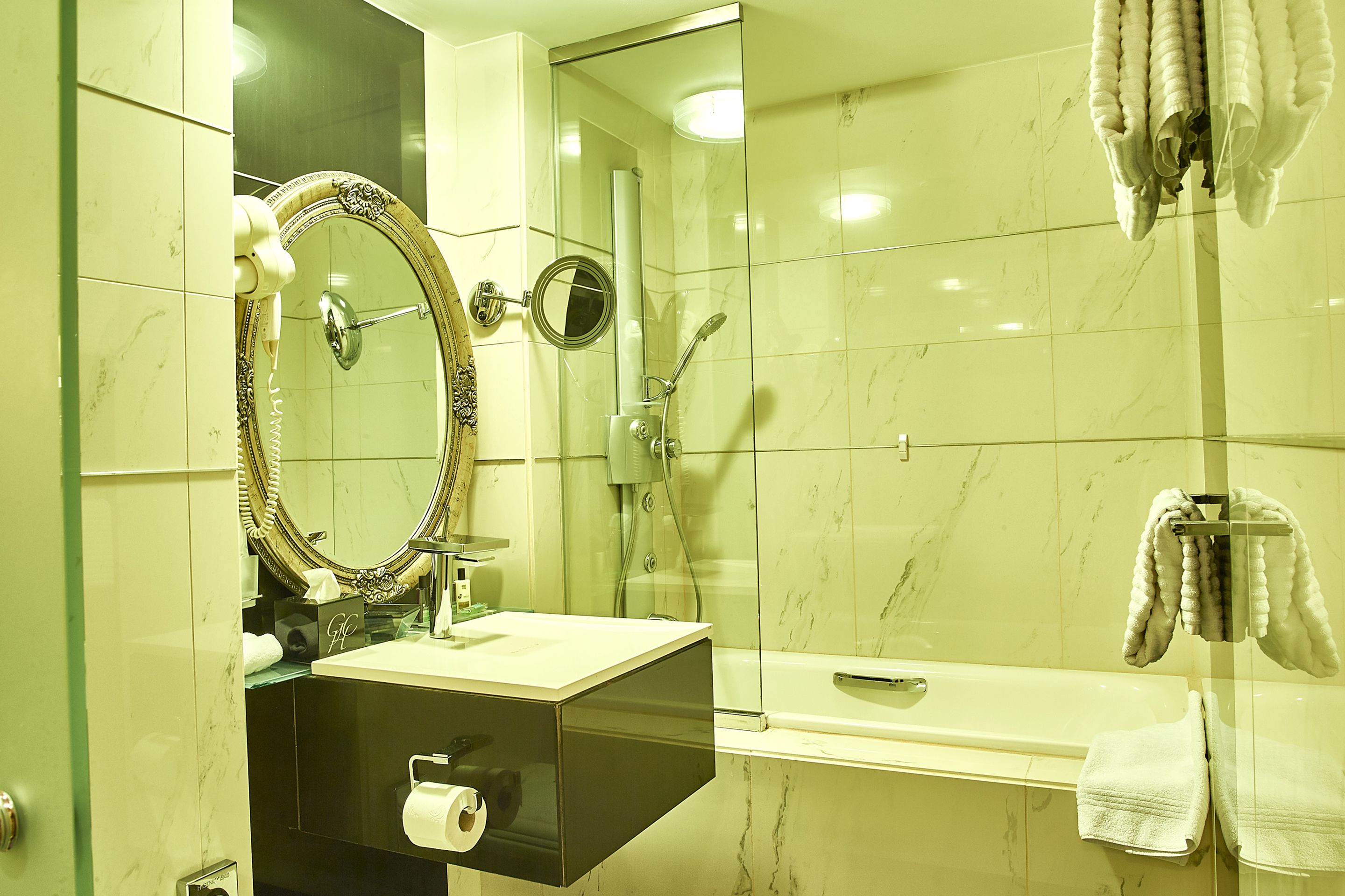 A bathroom with a glass-enclosed shower, a vanity with a mirror, and a towel rack.