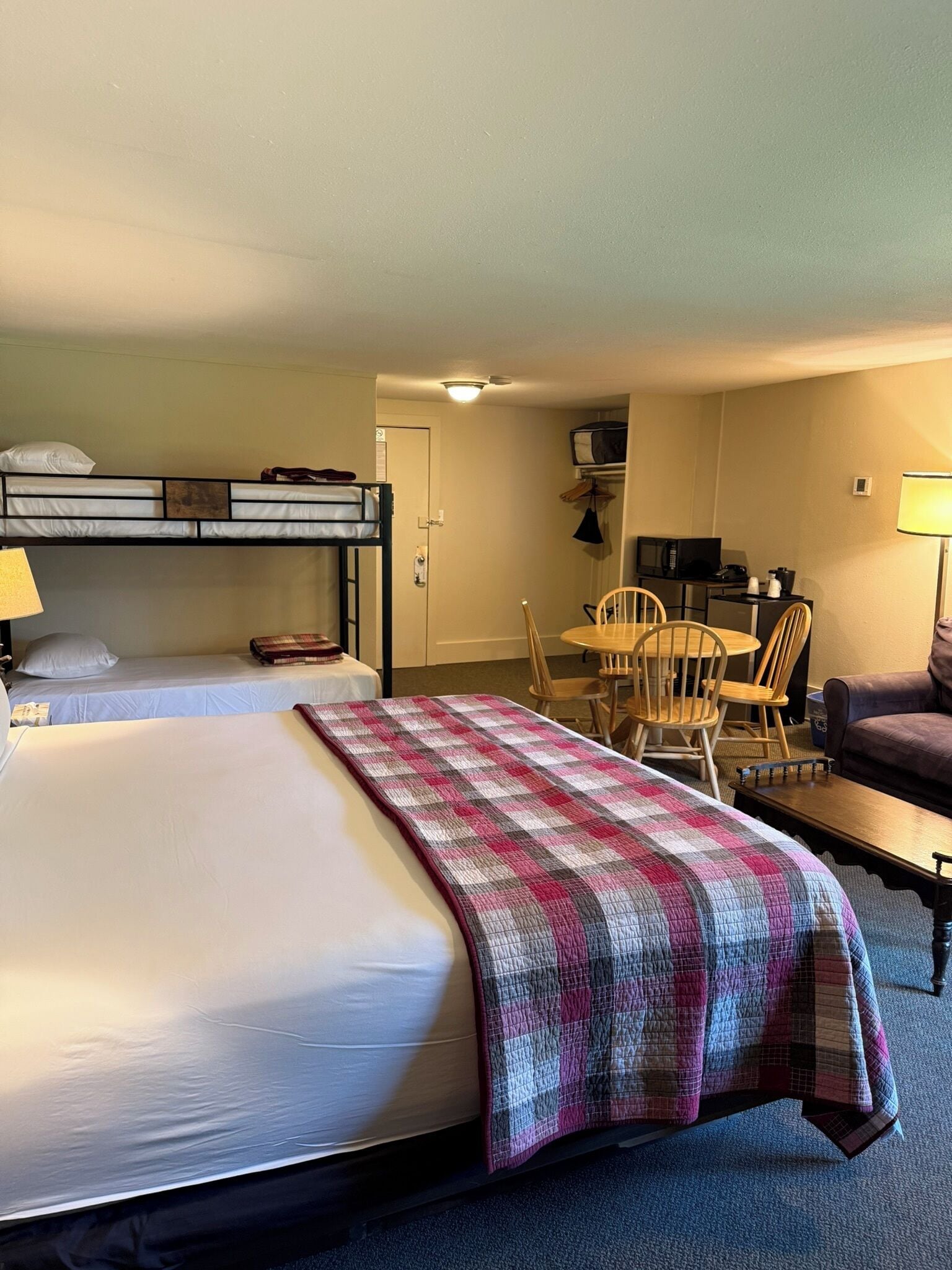 A hotel room with a large bed, a desk, a chair, a couch, and a television.