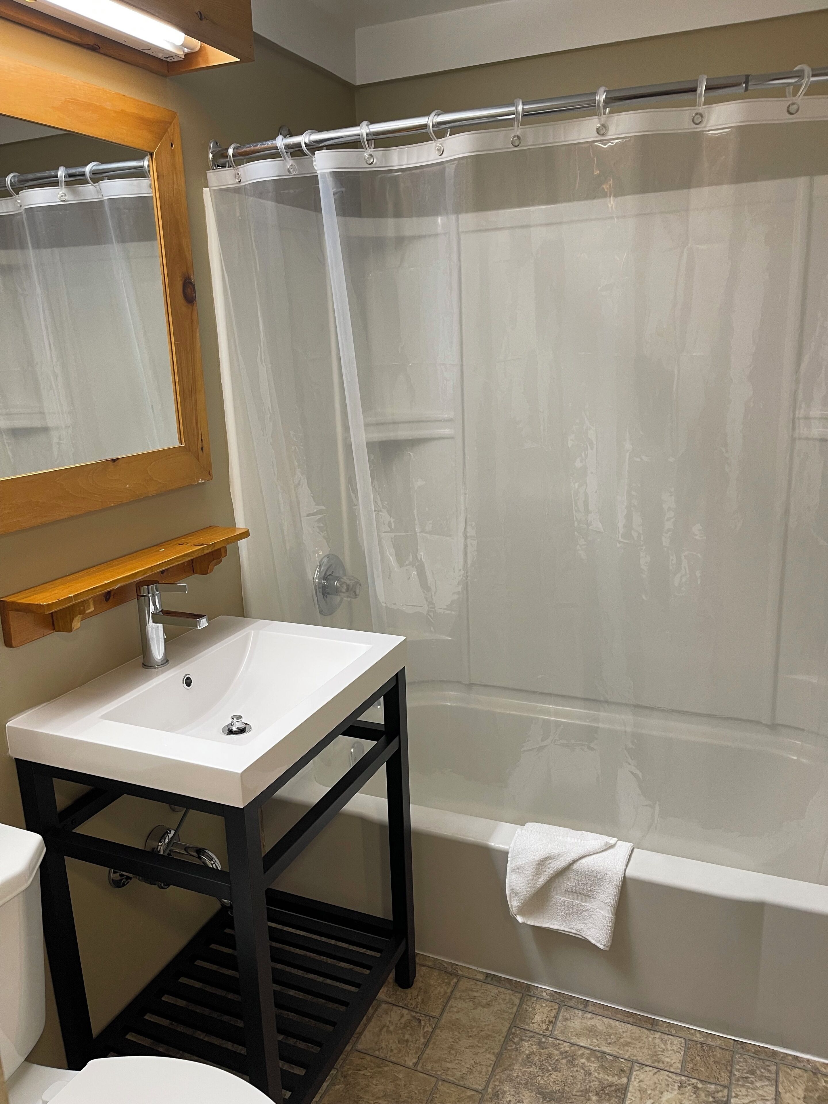 A bathroom with a white sink, a mirror, a shower curtain, and a bathtub.