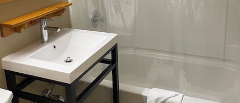 A bathroom with a white sink, a mirror, a shower curtain, and a bathtub.