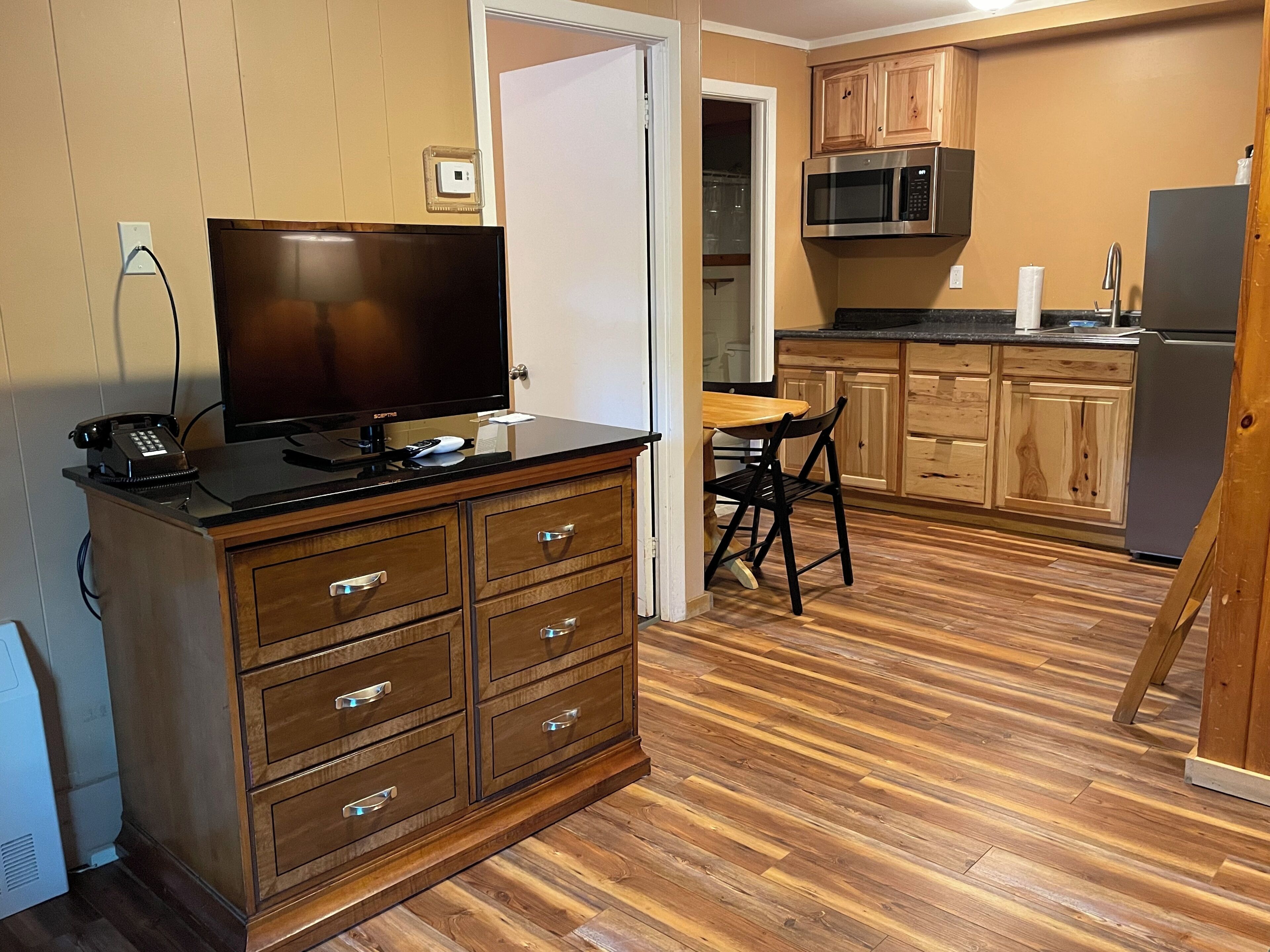 A compact kitchen with wooden cabinets, a microwave, and a refrigerator.