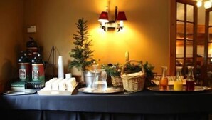 A buffet table with coffee, tea, and juice options, a small Christmas tree, and a candle. - Northern Lights Lodge (Stowe)