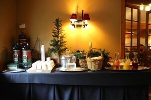 Una mesa de buffet con opciones de café, té y zumo, un pequeño árbol de Navidad y una vela.