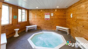 A wooden spa room with a hot tub, benches, and a caution sign for spa users. - Northern Lights Lodge (Stowe)