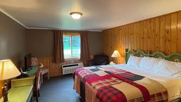 A hotel room with a bed, desk, chair, and a window with curtains.