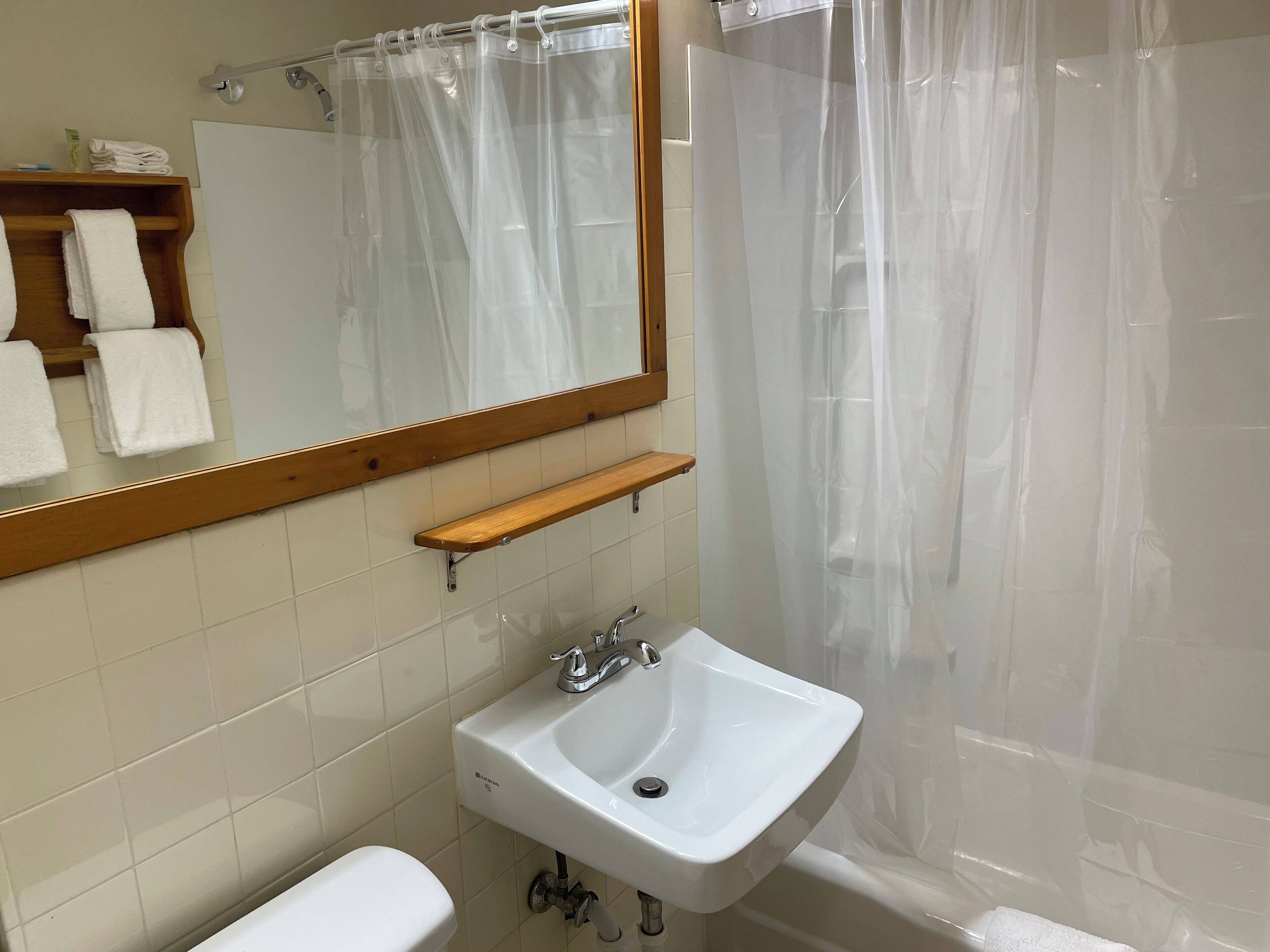 A bathroom with a white sink, a mirror, a shower curtain, and a toilet.