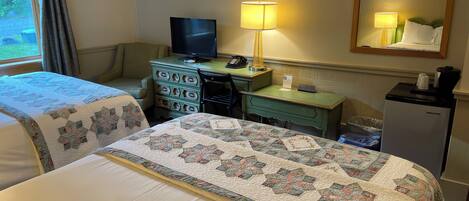 A hotel room with a bed, a desk, a television, a lamp, and a refrigerator.