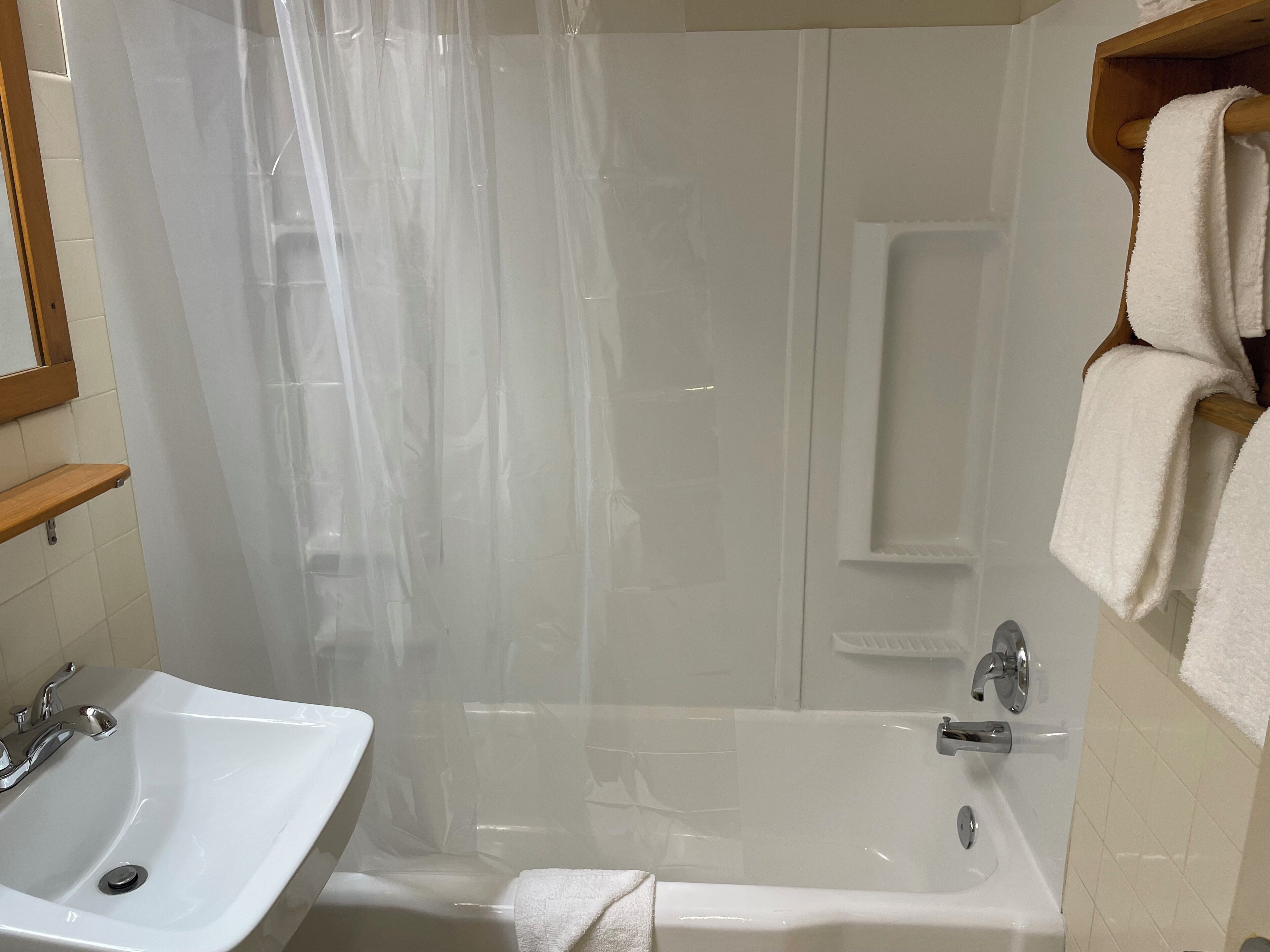 Un baño con lavamanos blanco, bañera y cortina de ducha.