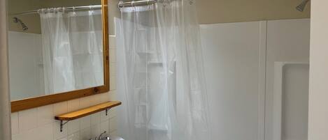 A bathroom with a white sink, a mirror with a wooden frame, a shower curtain, and a bathtub.