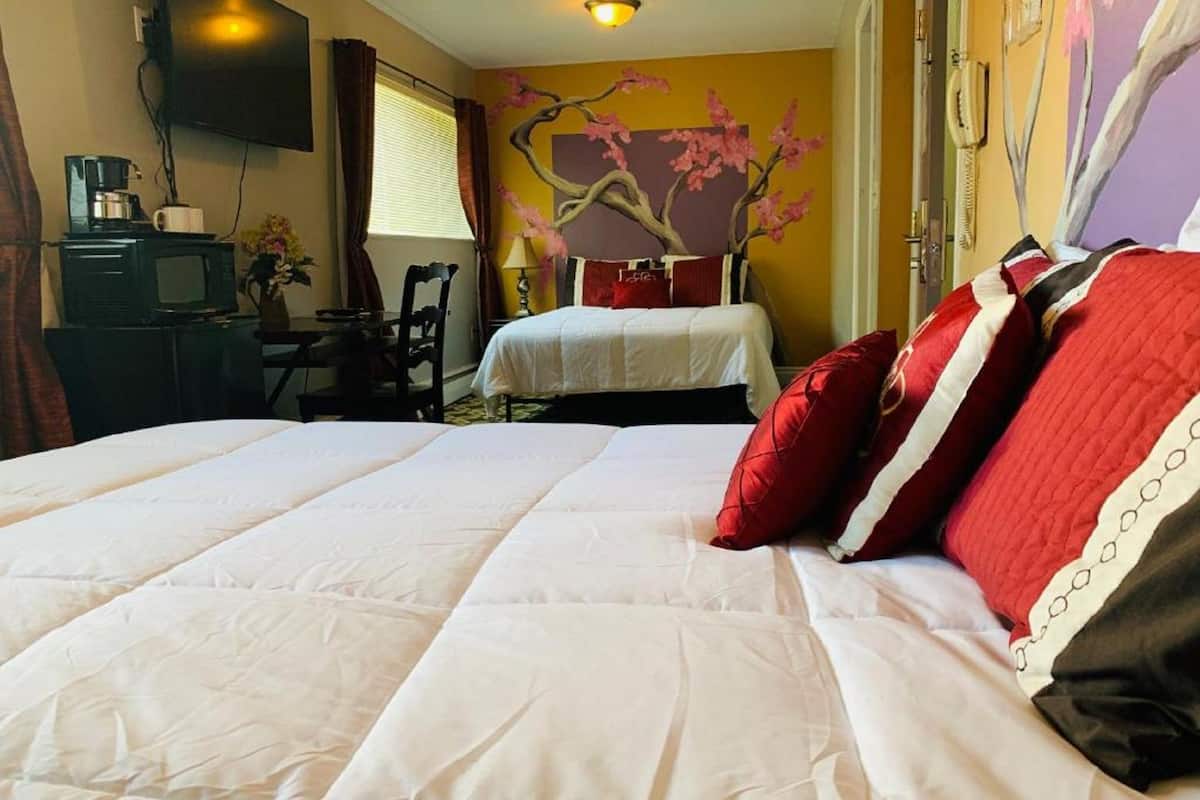 A hotel room with a large bed, a desk with a computer, a chair, and a television.