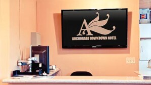 A reception desk with a television displaying the Anchorage Downtown Hotel logo. - Anchorage Downtown Hotel (Anchorage)
