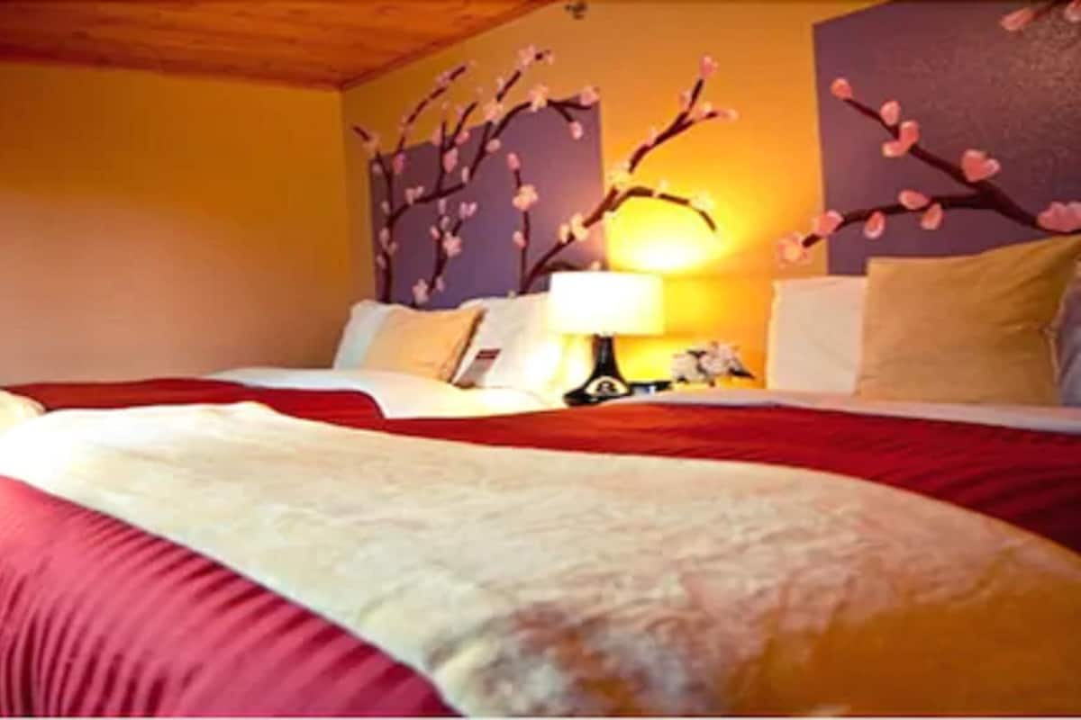 A hotel room with a bed, a nightstand, and a wall-mounted lamp.