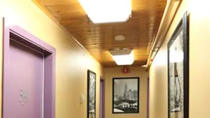 A narrow hallway with a purple door on the left, a framed picture on the wall, and a ceiling light. - Anchorage Downtown Hotel (Anchorage)