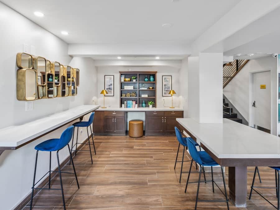 Une cuisine moderne avec une longue table à manger, des tabourets de bar bleus et un plancher en bois.