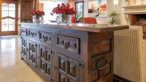 A reception area with a wooden counter, a vase of red flowers, and a painting on the wall. - Ayres Hotel Anaheim (Anaheim)