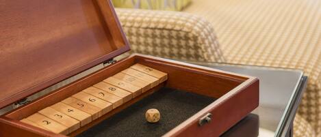 A wooden box with numbered compartments and a single dice on a dark surface.