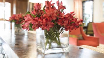 Un jarrón de vidrio transparente con flores rosas sobre una mesa de madera.