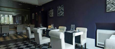 A dining area with checkered flooring, white chairs, and tables set for dining.