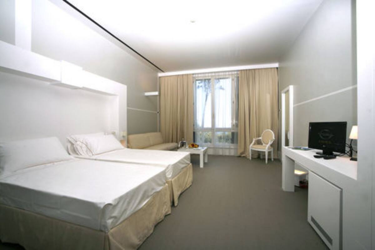 Een hotelkamer met een groot bed, een bureau met een computer, een stoel en een kleine tafel.