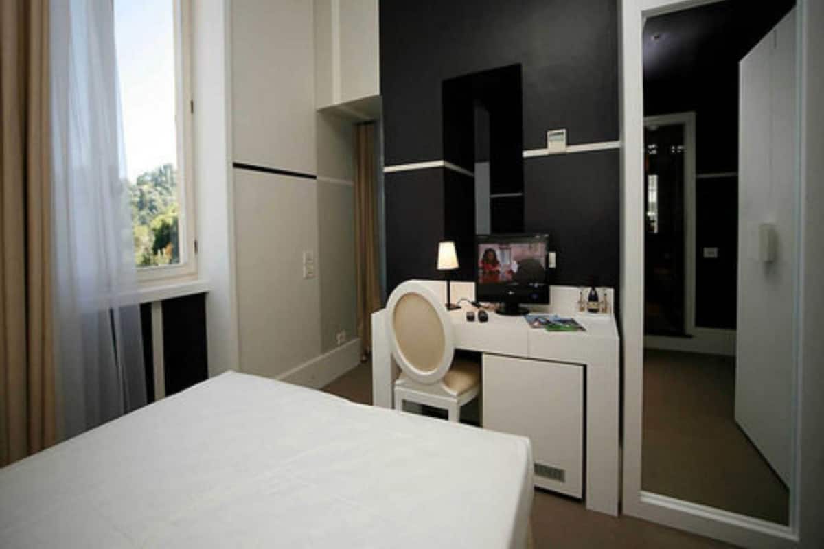 Een hotelkamer met een bed, een bureau, een stoel, een televisie en een raam met gordijnen.