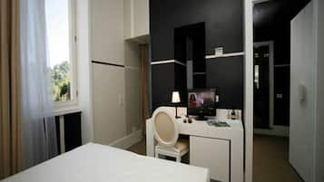 Una camera d'albergo con un letto, una scrivania, una sedia, una televisione e una finestra con tende.