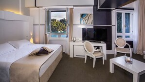 A hotel room with a bed, desk, TV, and seating area. - Hotel Piccolo Portofino (Portofino)