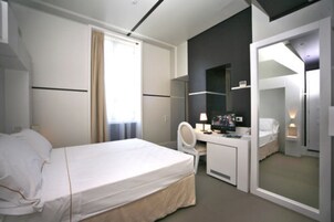 Habitación de hotel moderna con cama, escritorio, silla y un espejo grande.