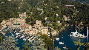 A coastal town with a marina filled with boats, surrounded by lush green hills and traditional buildings. - Hotel Piccolo Portofino (Portofino)