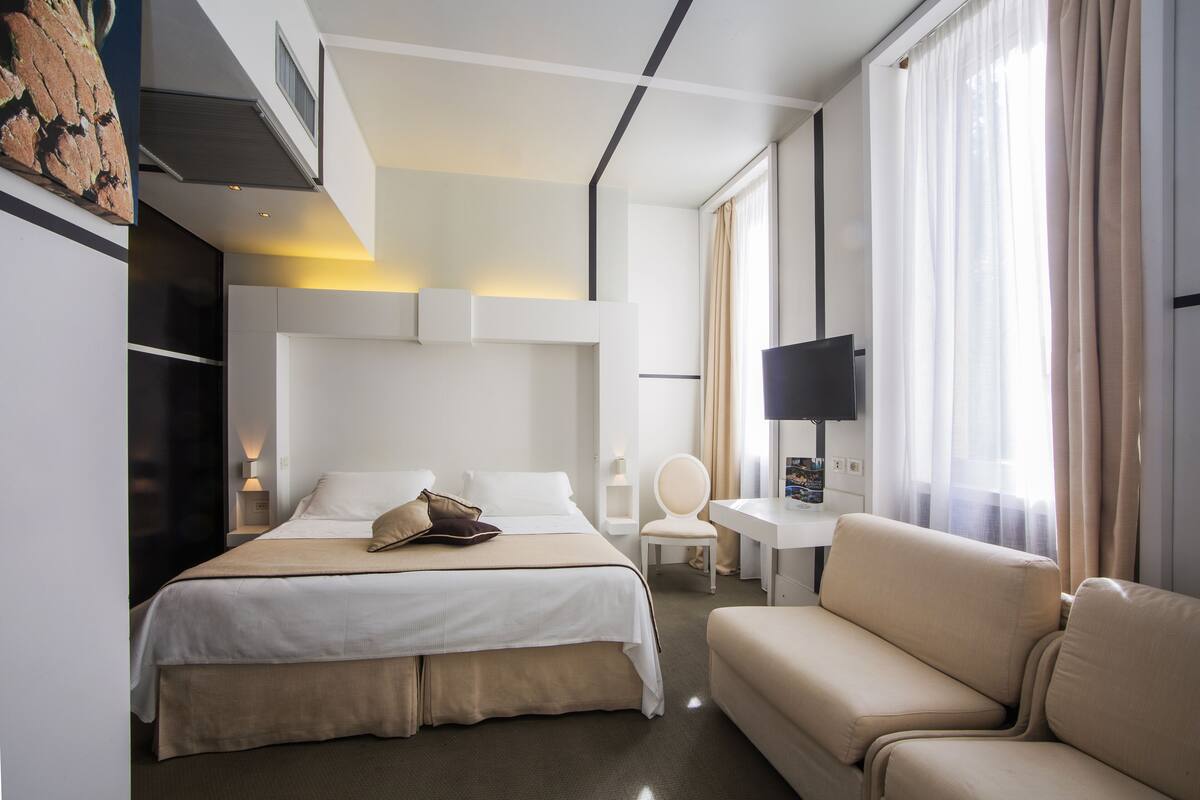 Een moderne hotelkamer met een groot bed, een bank, een bureau en een televisie.