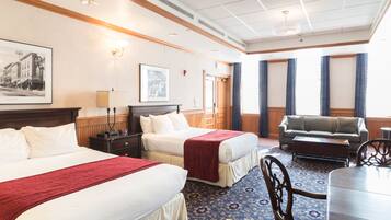 Een hotelkamer met twee bedden, een bank, een eettafel en een kroonluchter.
